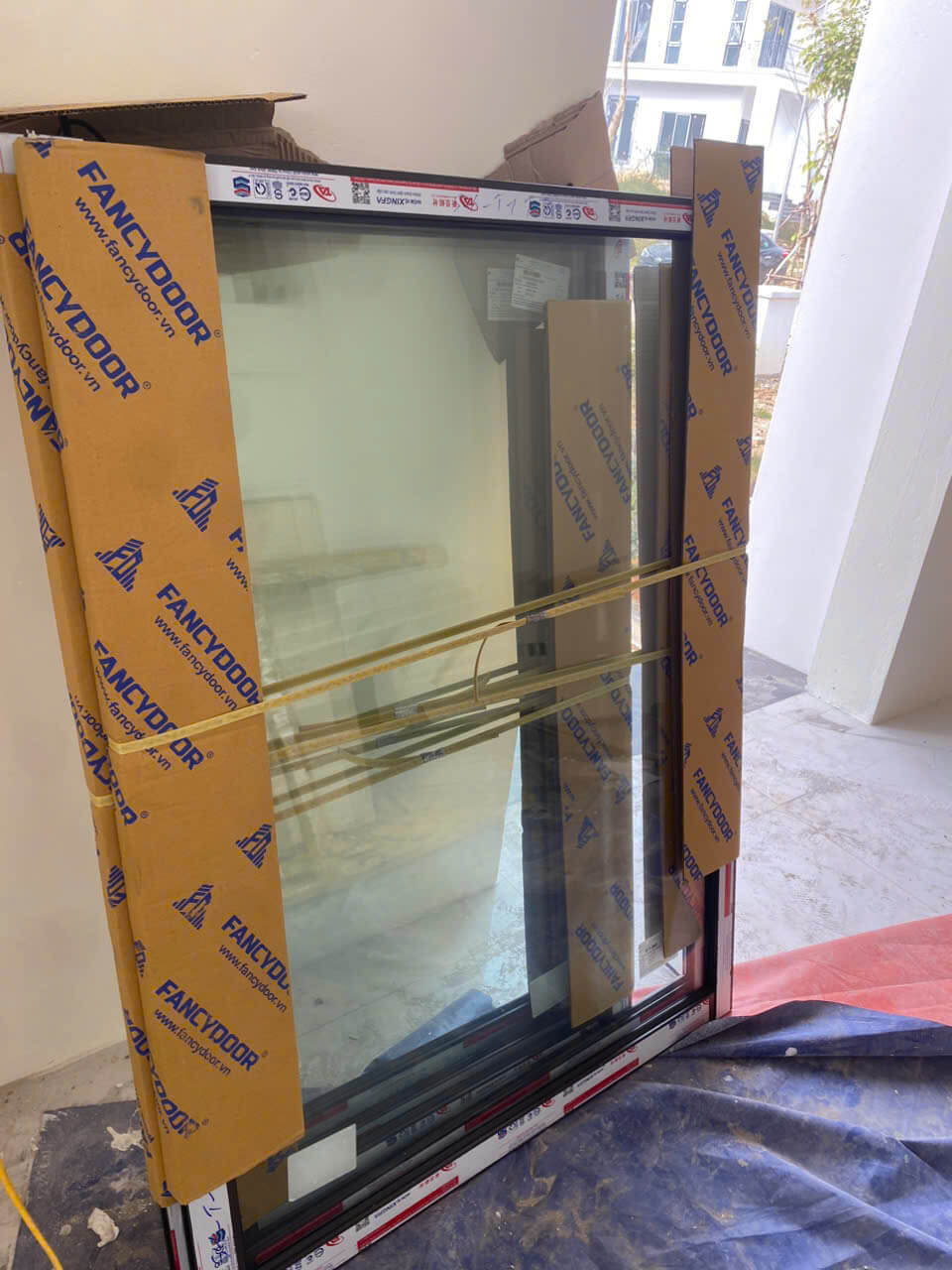 Cửa kính nhôm Fancydoor mới chưa lắp đặt được bọc carton trong công trình xây dựng